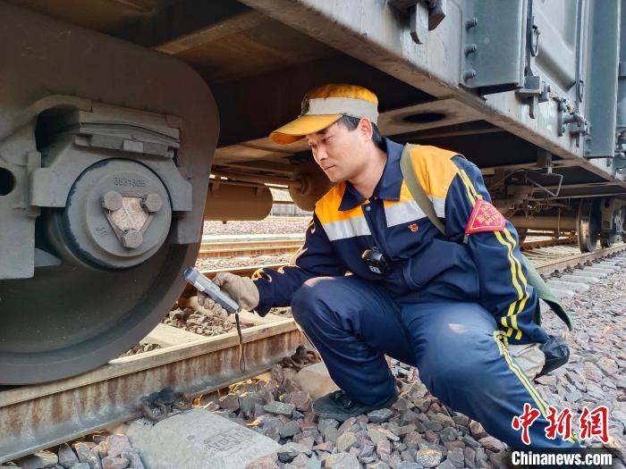 圖為張建亮在檢查車輛軸承溫度?!≈炜△?攝 圖為張建亮在檢查車輛軸承溫度?!≈炜△?攝
