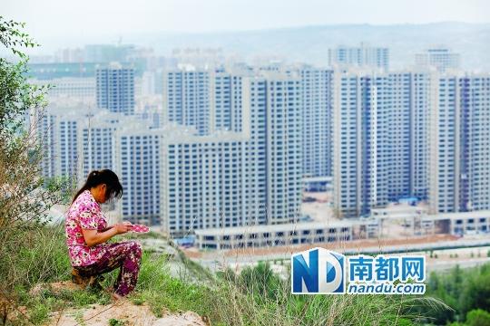 神木新村西面的山坡上,一名磚窯的員工坐在坡頂繡鞋墊。席卷神木的民間借貸危機(jī)壓垮了當(dāng)?shù)貥鞘幸惨l(fā)債務(wù)危機(jī),高樓林立的神木新村今年大部分工程已經(jīng)停工。南都記者孫俊彬攝