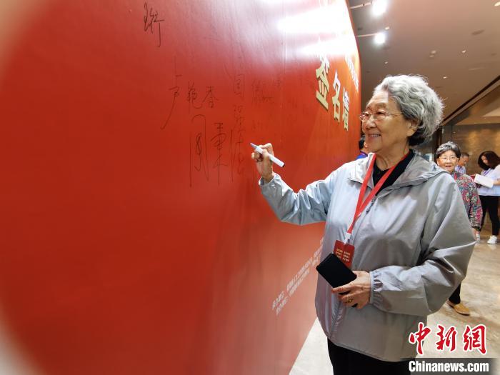 圖為中國(guó)新聞社原副社長(zhǎng)周秉德簽字留念?!∑钤鲚?攝 圖為中國(guó)新聞社原副社長(zhǎng)周秉德簽字留念?!∑钤鲚?攝